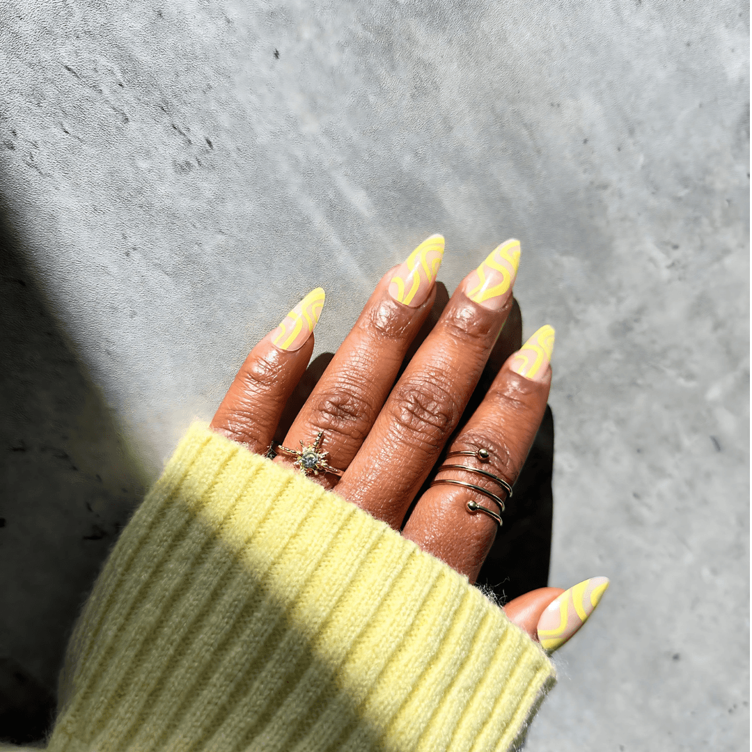 Hand with yellow almond press-on nails and rings