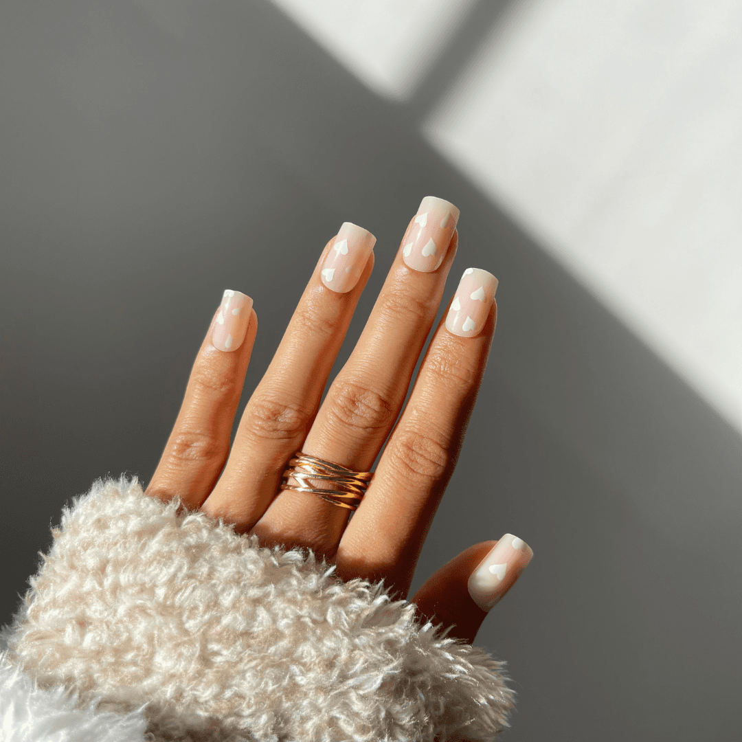 Square-shaped nude press-on nails with heart design.