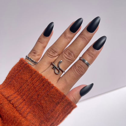 Hand with black almond press-on nails and rings