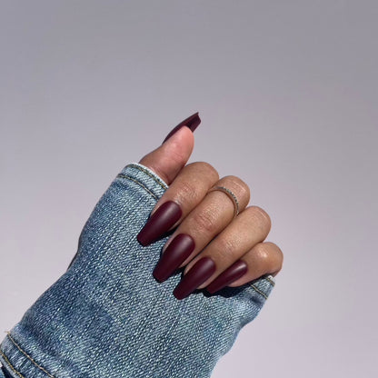 Hand with medium length burgundy press-on nails