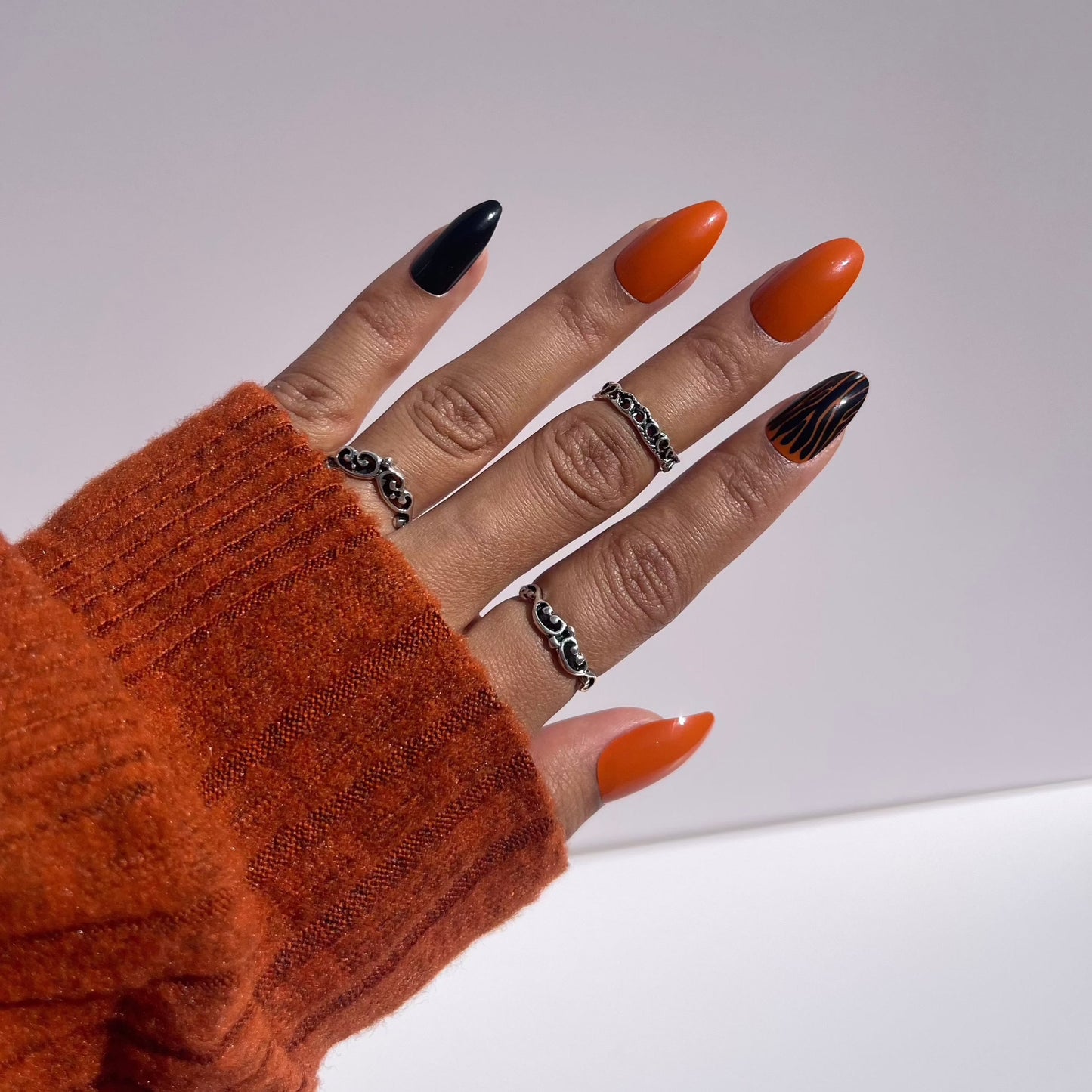 Stylish Halloween press-on nails in orange and black with zebra accents