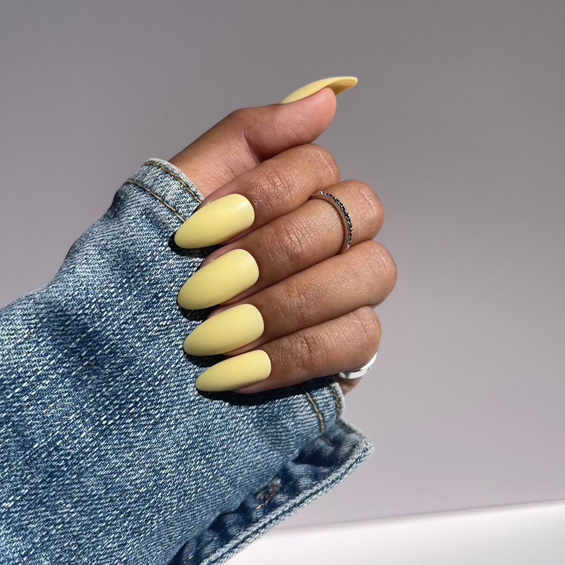 Pastel yellow almond press-on nails with denim sleeve