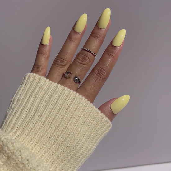 Trendy pastel yellow nails with cream sweater