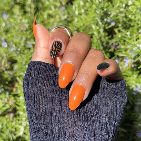 Close-up of Halloween press-on nails in orange and black with zebra design